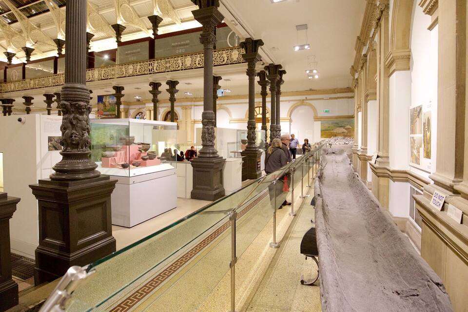 An indoor museum with classical architecture, including ornate columns and a glass railing.