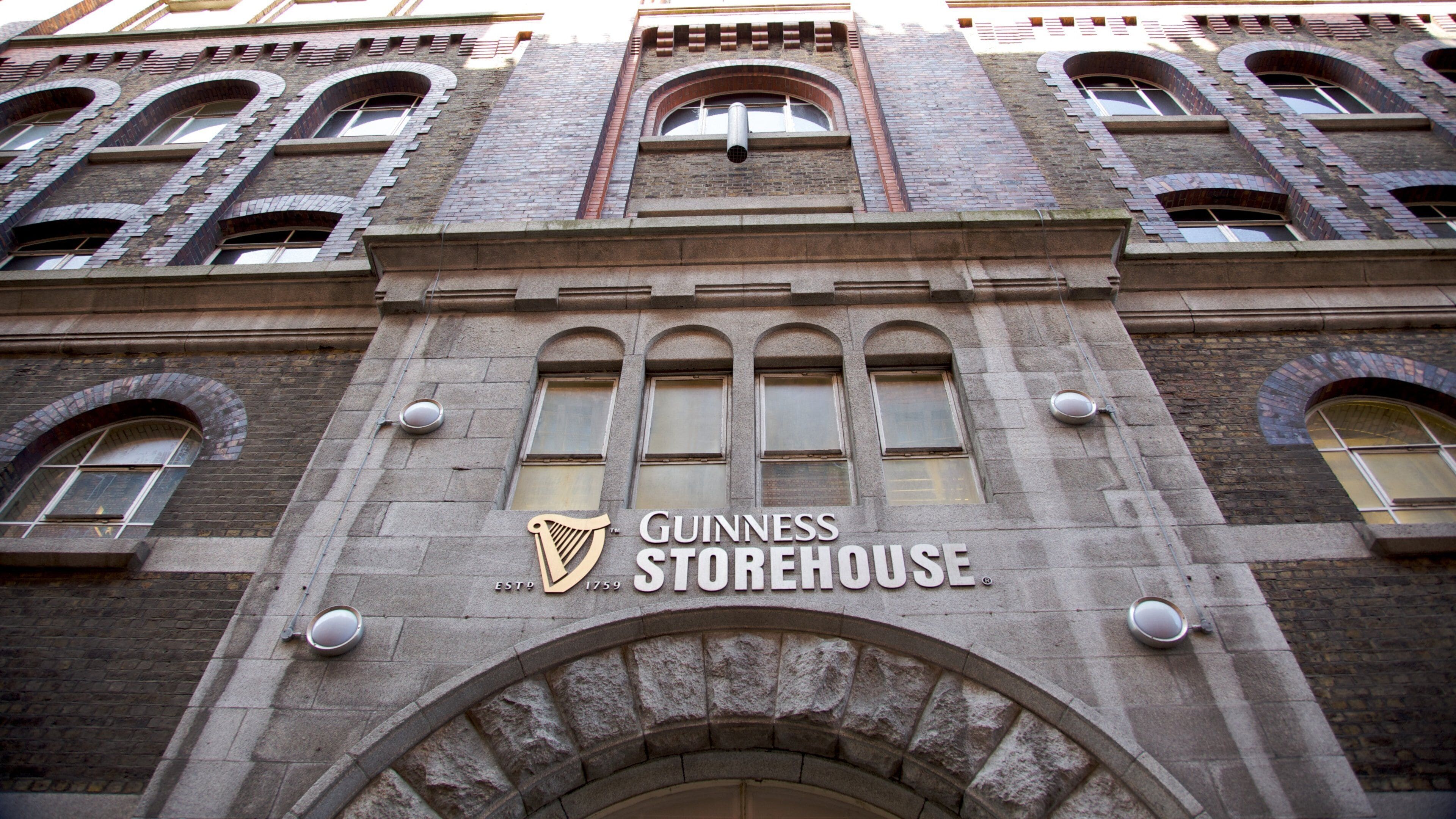 The exterior of the Guinness Storehouse building with its distinctive arched windows and stone facade.