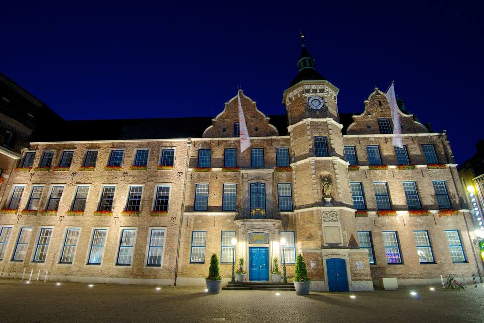En historisk byggnad med ett klocktorn, stora fönster och en blå dörr.