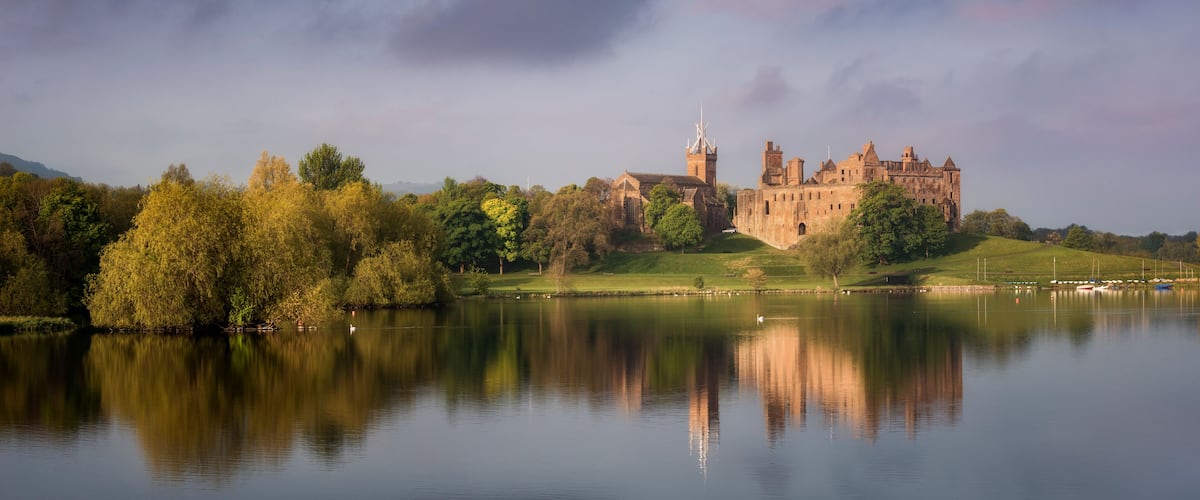 A castle on a hill with a lake in the foreground.