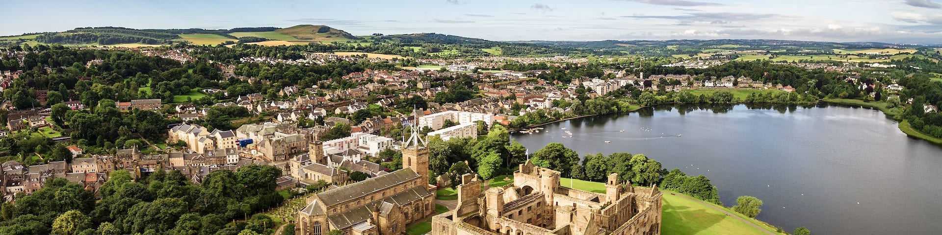The skyline of Linlithgow including the ruins of Linlithgow Palace and St. Michael's church from the air. Linlithgow, West Lothian, Scotland.