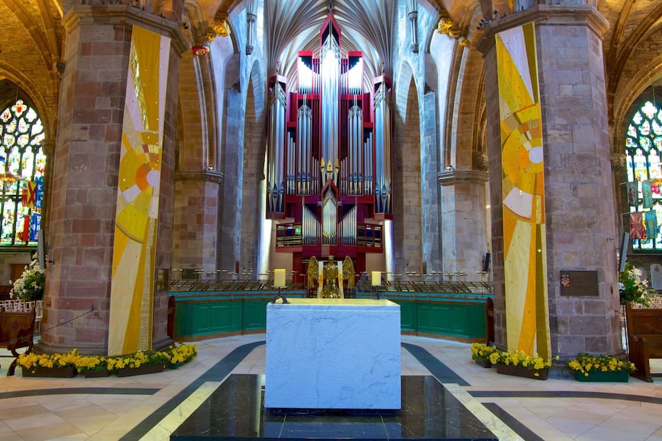 Een kerkinterieur met een groot orgel, glas-in-loodramen en bloemdecoraties.