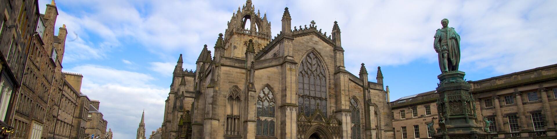 A historic cathedral with intricate Gothic architecture, a statue, and a cobblestone square.