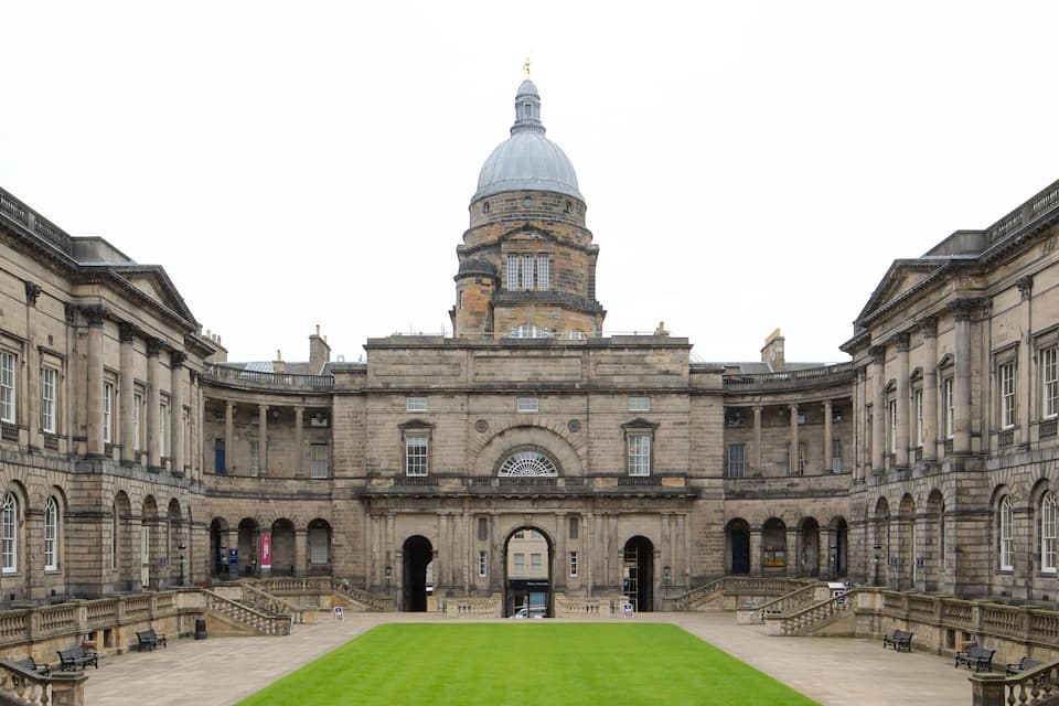 A historic building with a central dome and symmetrical wings.