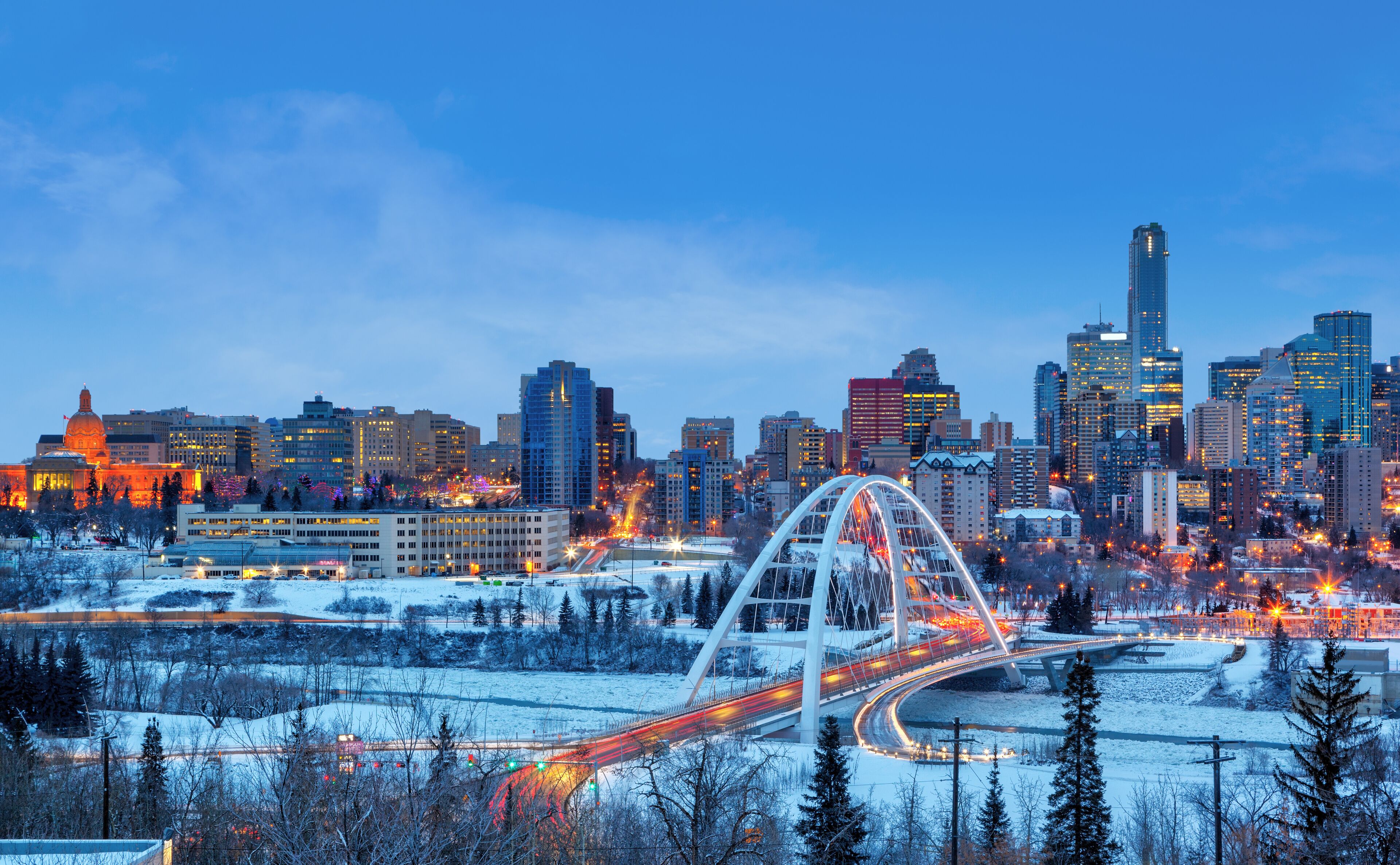 Edmonton Downtown Skyline Just After Sunset in the Winter Showing Alberta Legislature and Walterdale Bridge Over the frozen Saskatchewan River
