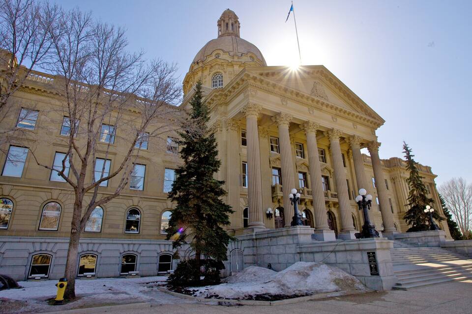 A large neoclassical building with a dome and columns, surrounded by trees and snow.