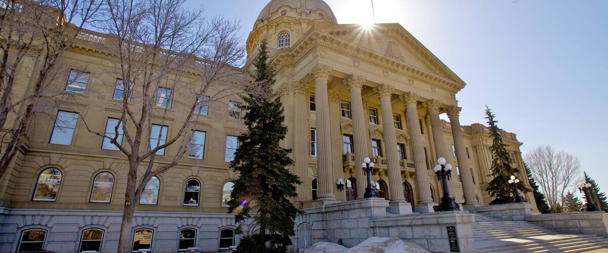 A large neoclassical building with a dome and columns, surrounded by trees and snow.