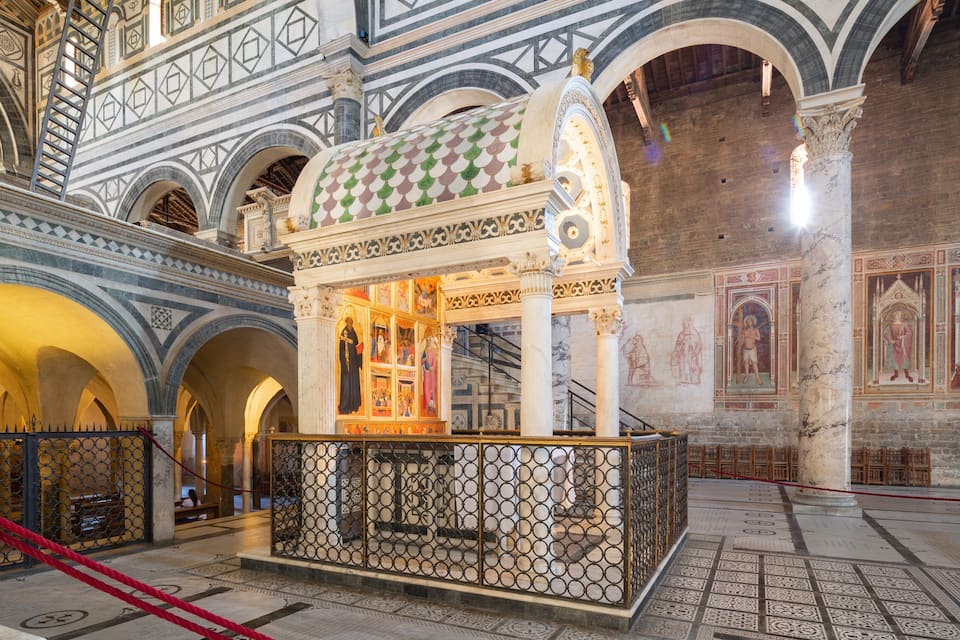 Interior d'església amb sostre de mosaic, voltes allargades i un altar central amb teulada de disseny verd i blanc.