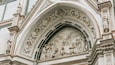 A detailed stone facade with intricate carvings and a central relief sculpture depicting a religious scene.