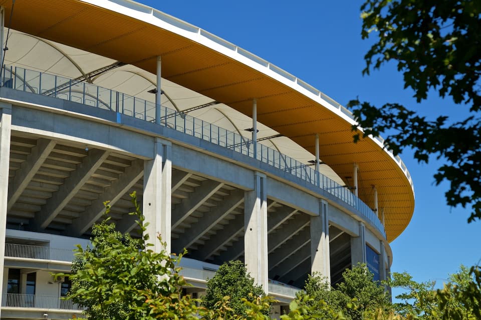 Een groot, modern stadion met een gebogen dak en meerdere niveaus van zitplaatsen.