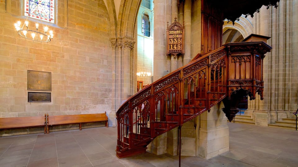 Un magnifique escalier orné de sculptures complexes, des murs en pierre et des vitraux dans un bâtiment historique.