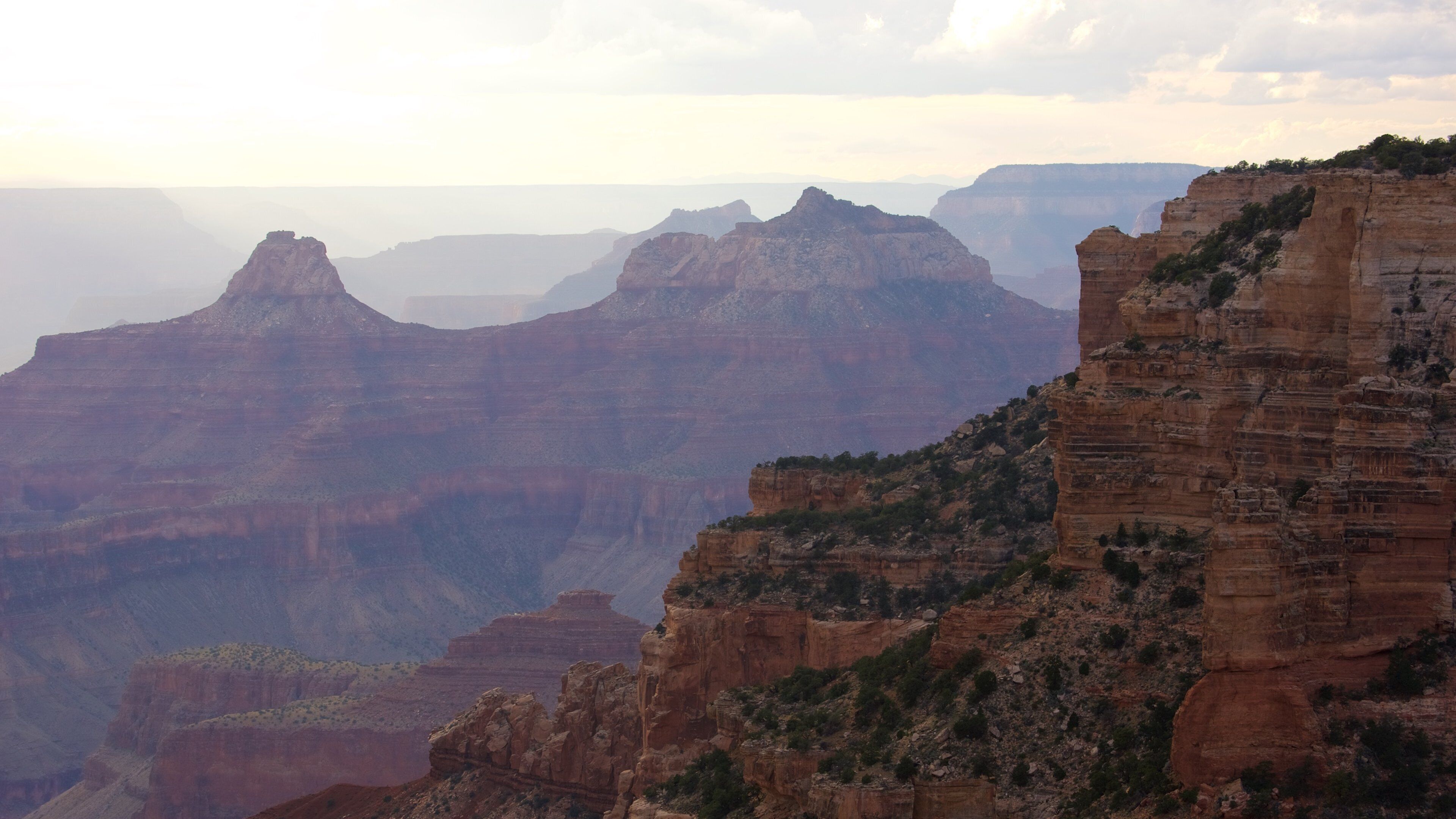 A canyon with layered rock formations and sparse vegetation.