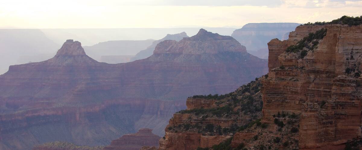 A canyon with layered rock formations and sparse vegetation.