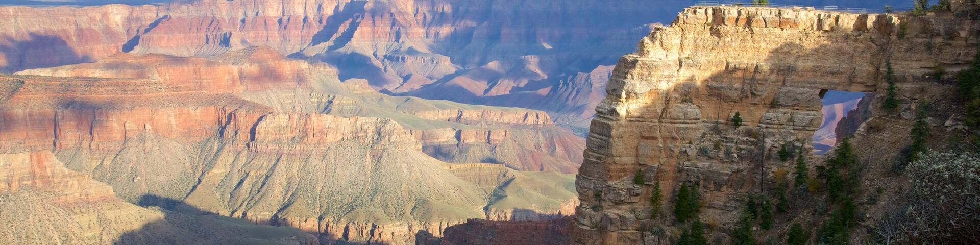 A canyon with layered rock formations and sparse vegetation.