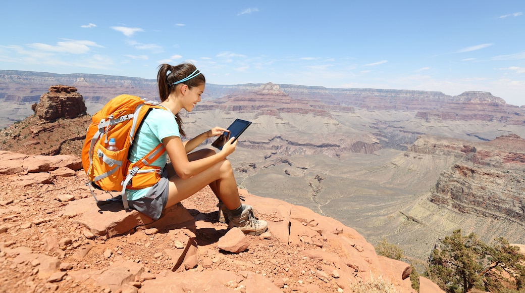 Tablet computer woman hiking in Grand Canyon using travel app or map during her hike. Multiethnic hiker girl relaxing on South Kaibab Trail, south rim of Grand Canyon, Arizona, USA.