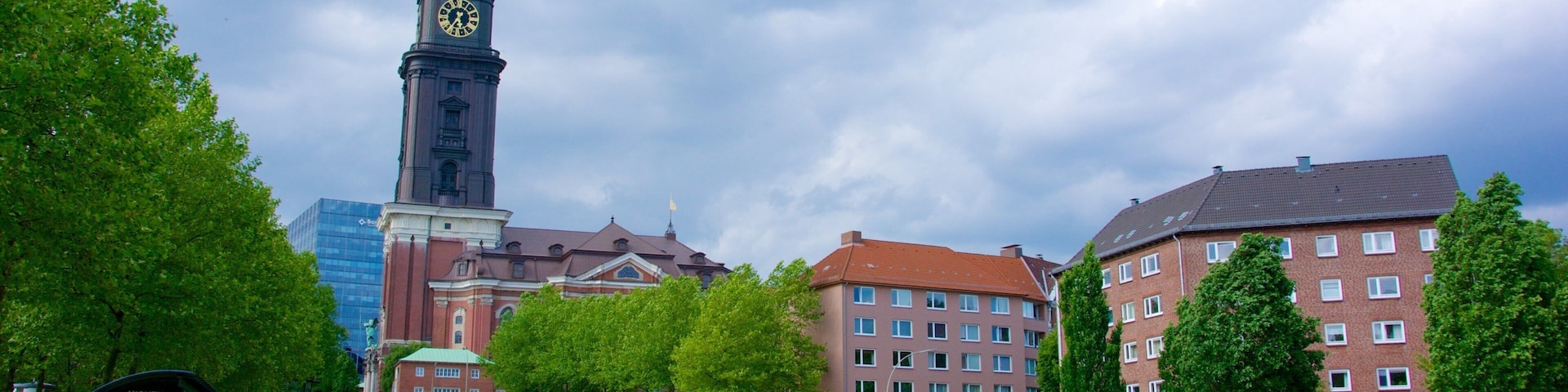 Ein Park mit einem Glockenturm, grüner Wiese und Gebäuden aus rotem Backstein.