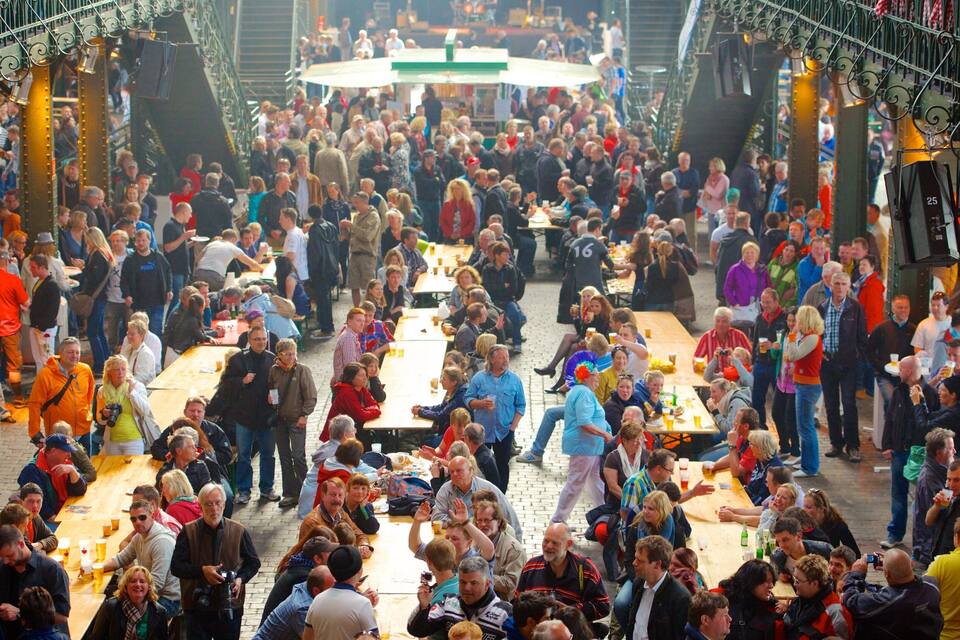 A crowded outdoor market with numerous tables and people.
