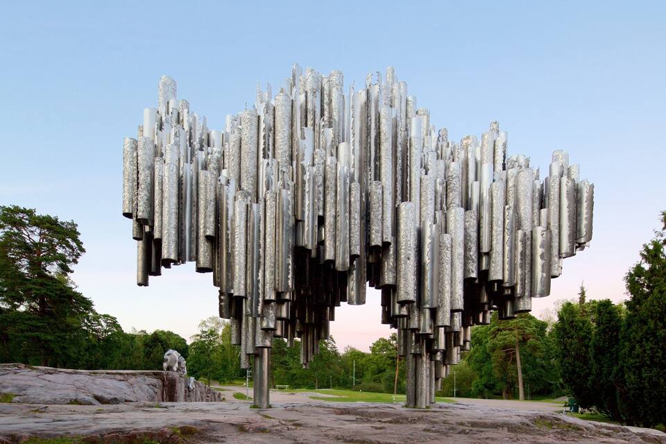 A sculpture of numerous cylindrical shapes in a park.