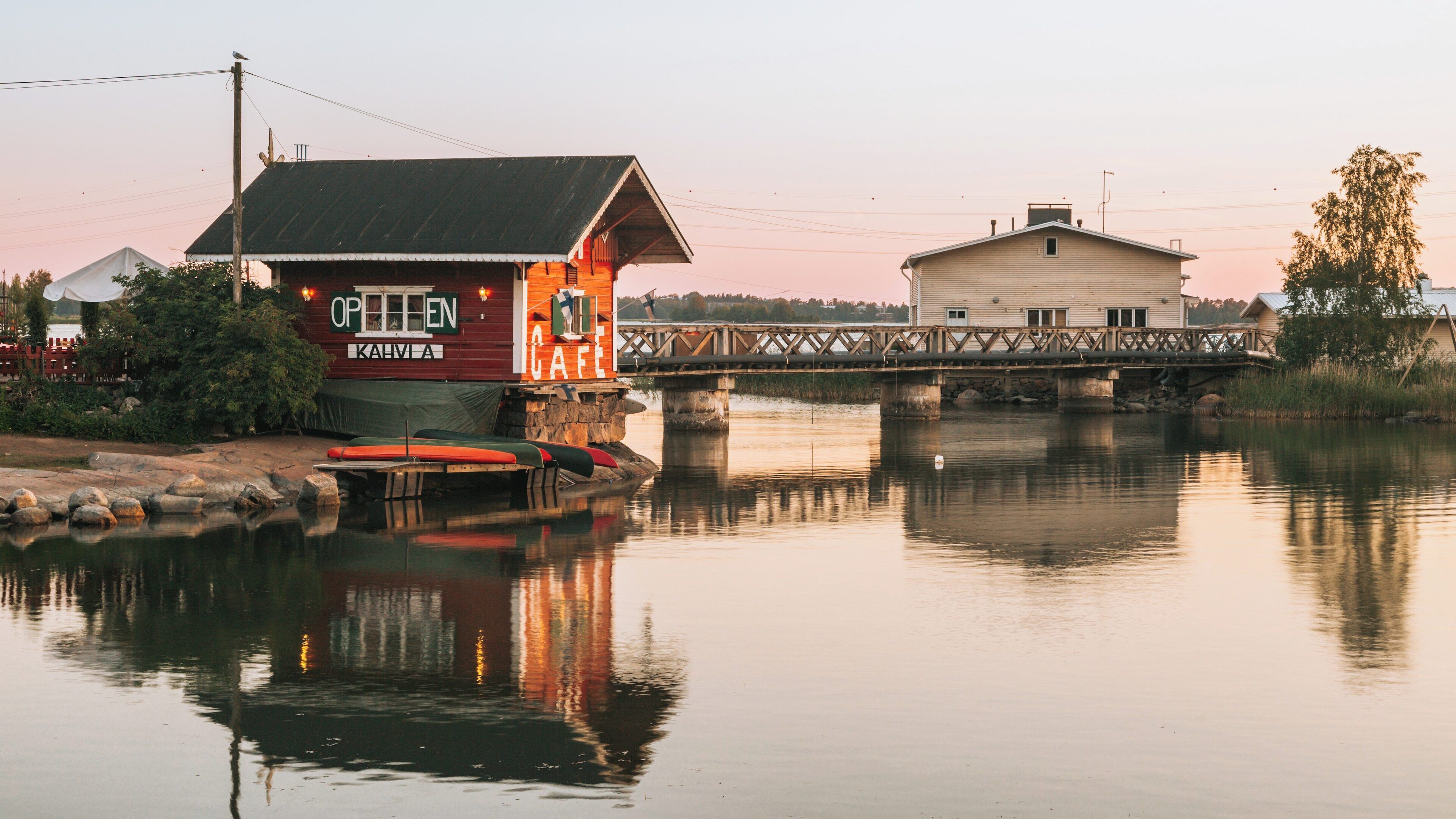 Sibelius Monument reflecting on a quiet waterway in Etelainen District, Helsinki showcases Finland's cultural heritage and natural beauty at sunset