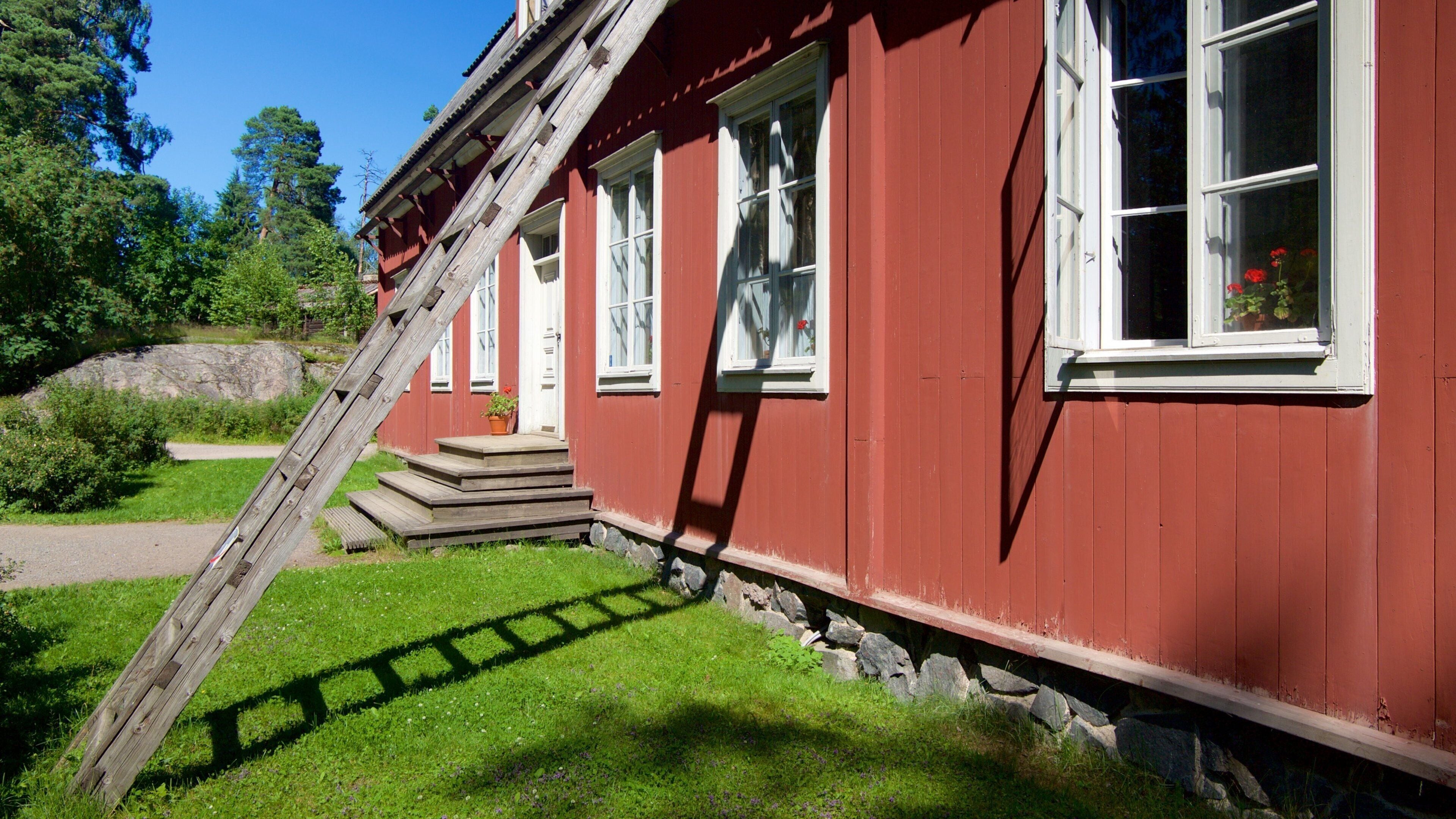 Et rødt træhus med hvide vinduer og en trætrap op til døren.