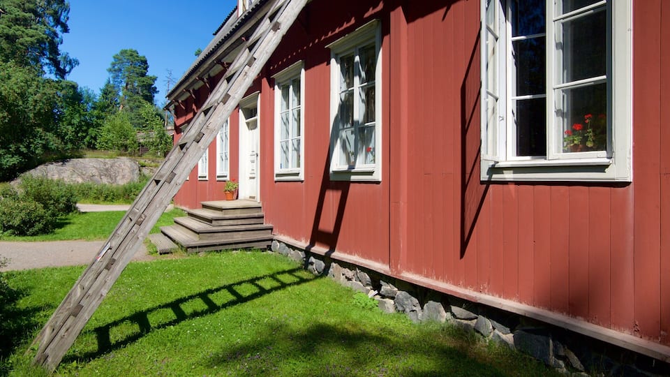 Une maison en bois rouge, avec des fenêtres blanches et un escalier en bois menant à la porte.