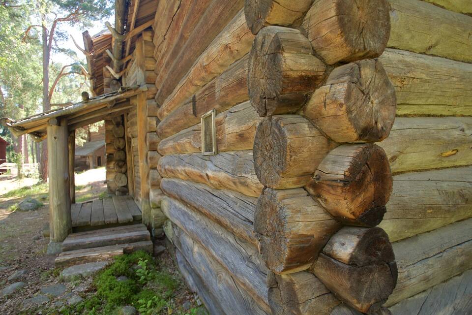 A rustic log cabin with a wooden porch and a stone foundation.