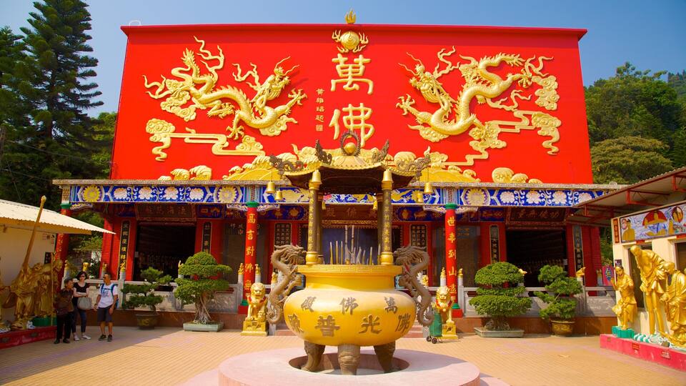 A temple with a red facade, golden dragons, and a large golden statue.