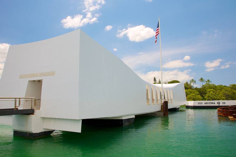 The USS Arizona Memorial in Pearl Harbor, with a clear view of the memorial's white structure and the American flag atop.