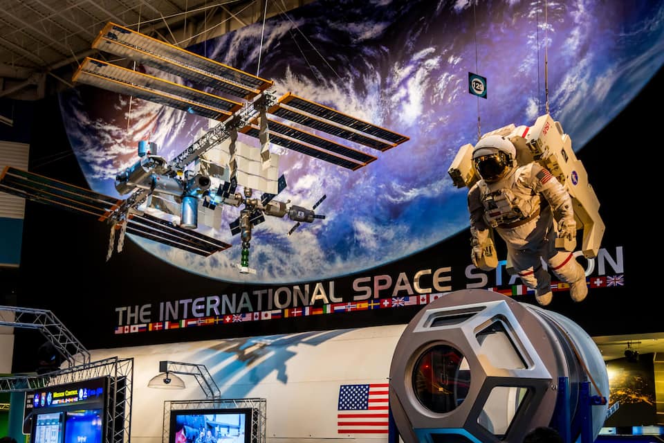 En utställning om rymden med en rymdfärja, en astronaut och en stor amerikansk flagga.