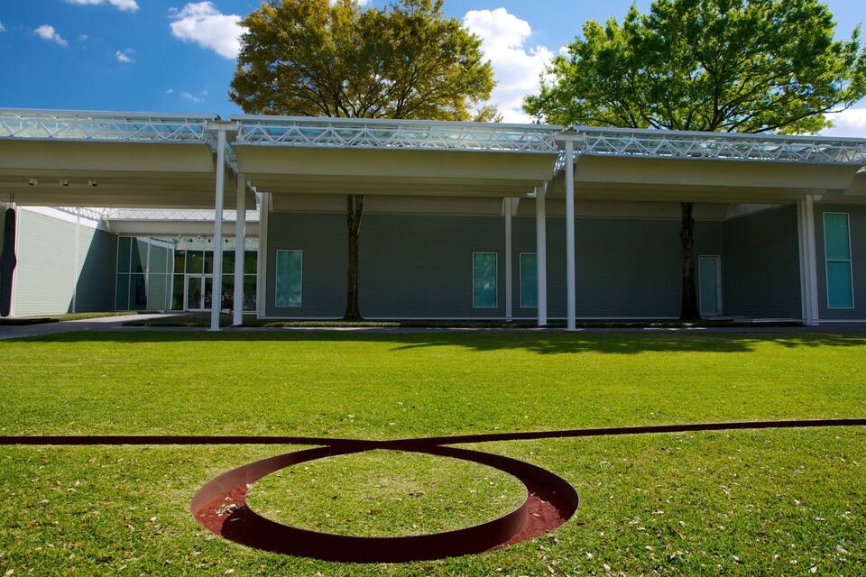 A modern building with a covered outdoor area and a circular garden feature.