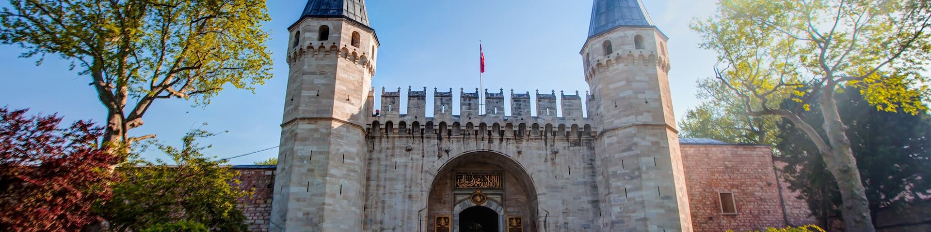 A historic stone gate with two towers, a clear sky, and a pathway leading to the entrance.