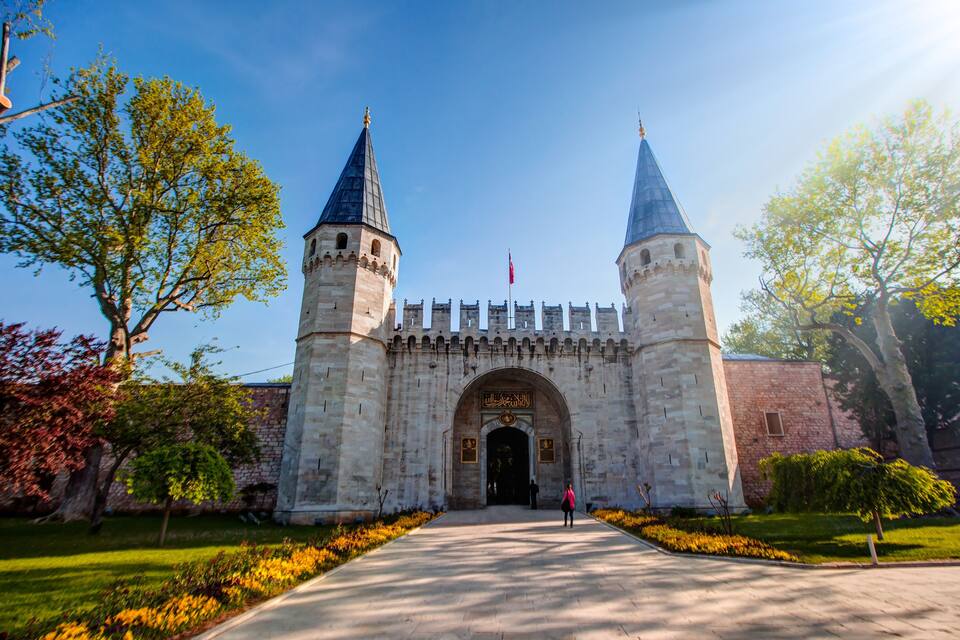 A historic stone gate with two towers, a clear sky, and a pathway leading to the entrance.