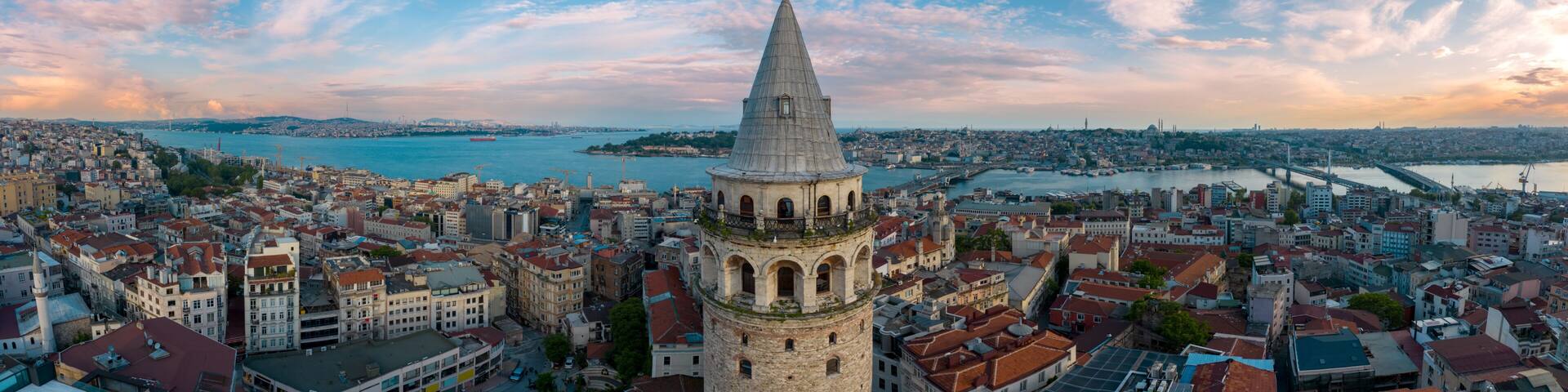 Panoramic view of Galata Tower and Istanbul Bosphorus with a cloudy sky.