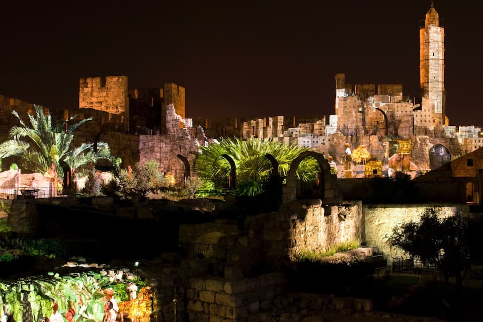 Un paisaje urbano histórico de noche con edificios iluminados y una torre destacada.