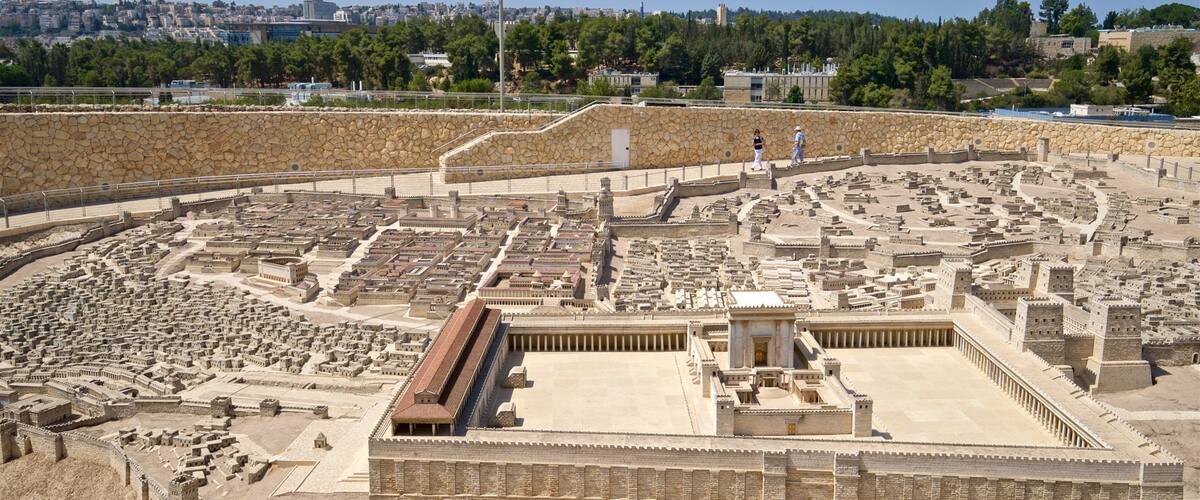 A detailed model of an ancient city with a central open area, surrounding walls, and a distant cityscape.