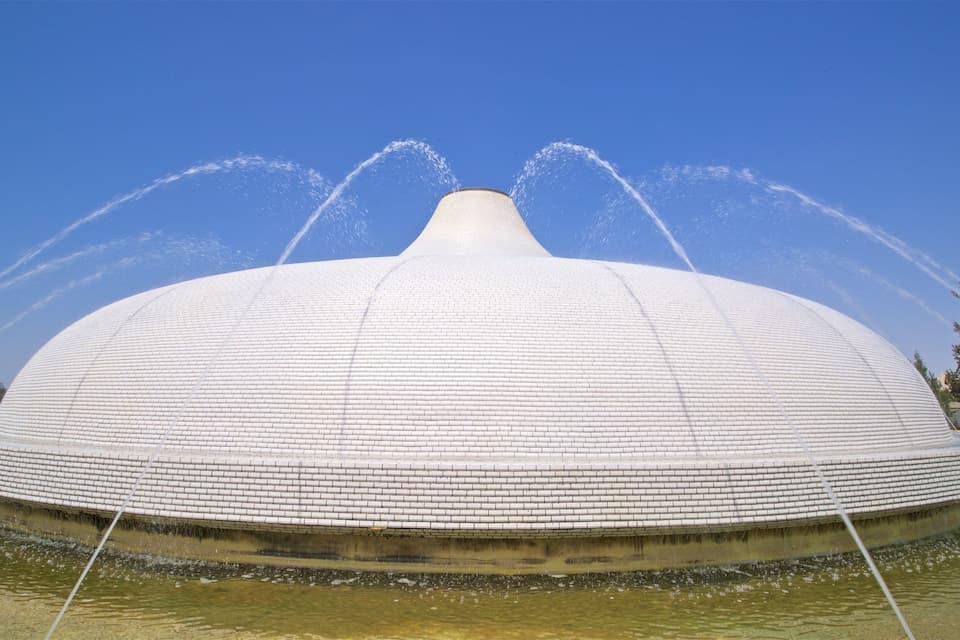 Uma grande estrutura em forma de cúpula branca, com jatos de água saindo do topo.