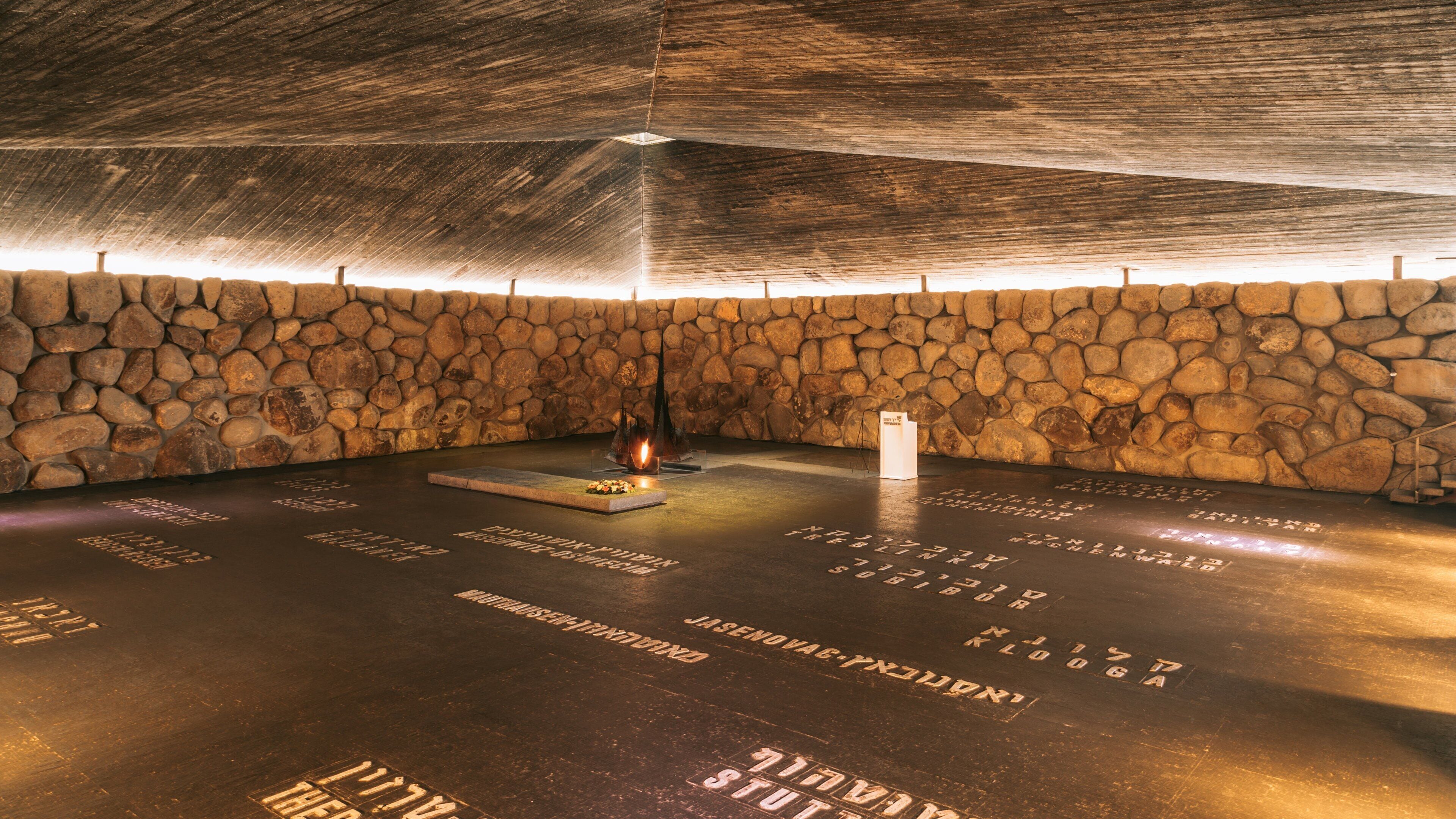 Um quarto com paredes de pedra, lareira e nomes gravados no chão.