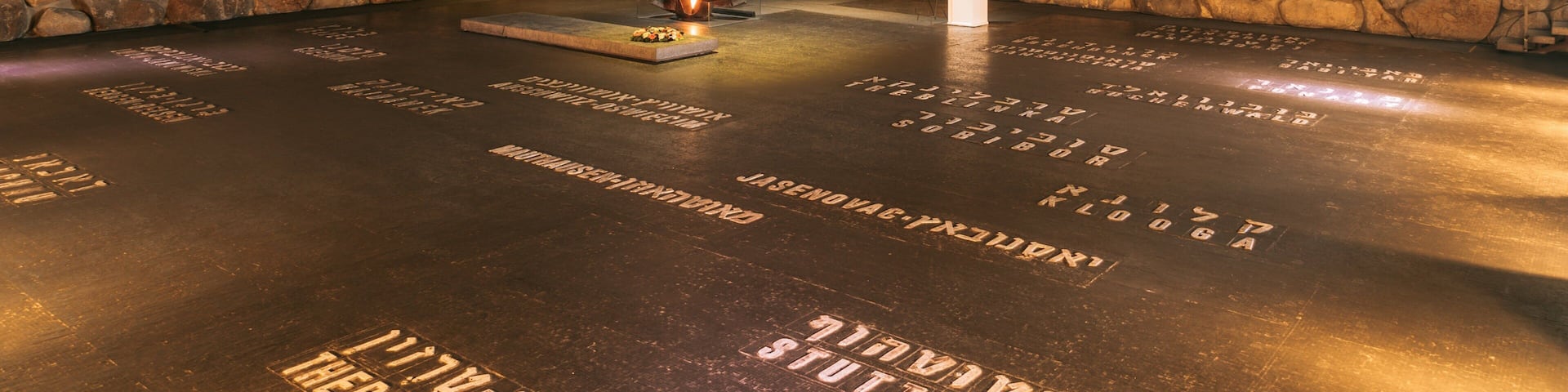 A stone-walled room with a fire feature and engraved names on the floor.