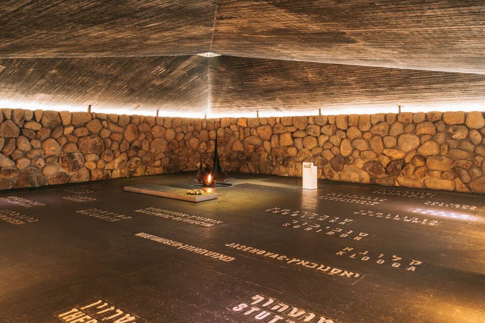 Um quarto com paredes de pedra, lareira e nomes gravados no chão.