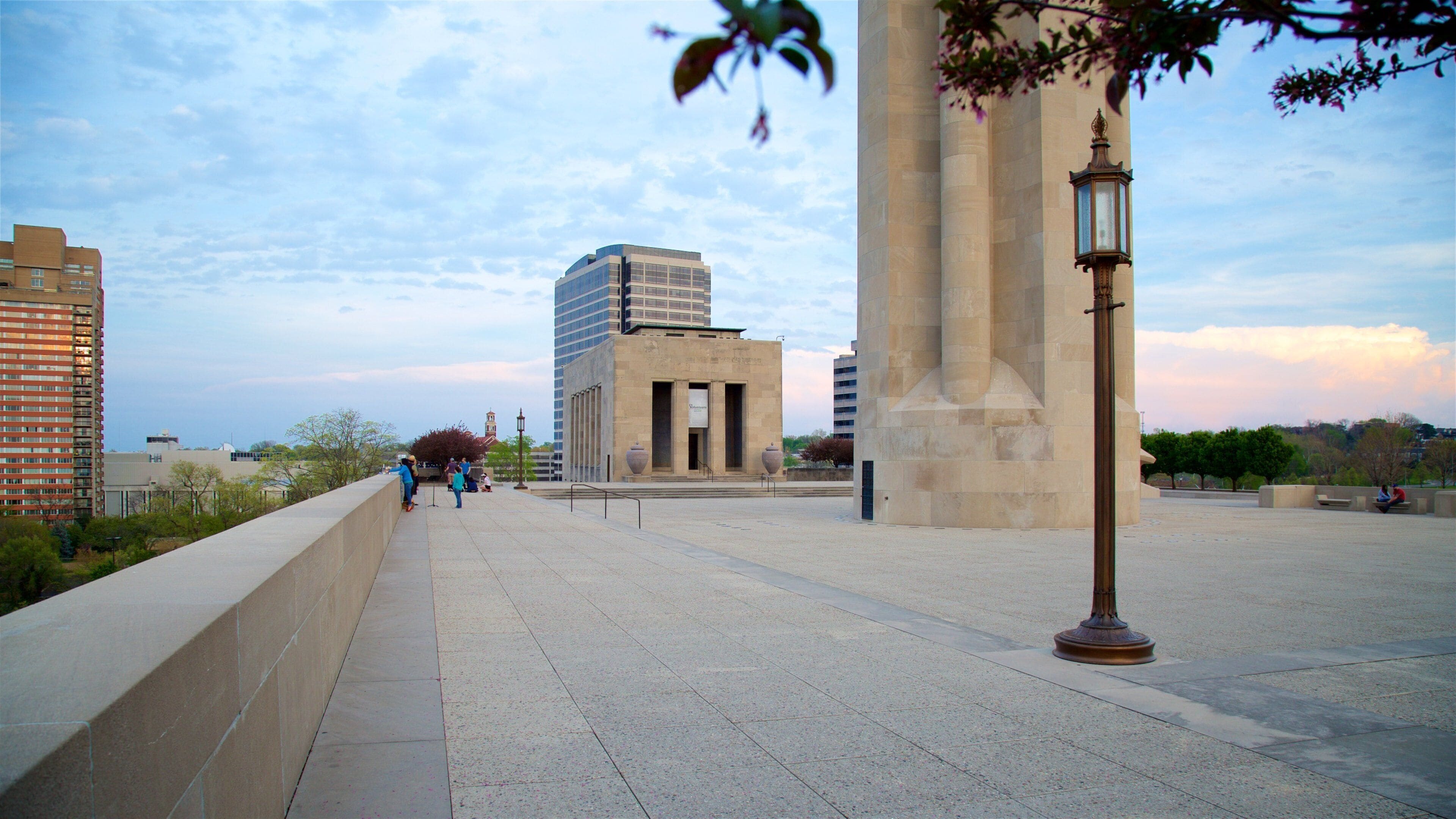 A city plaza with a large monument, a tall building, and a street lamp.
