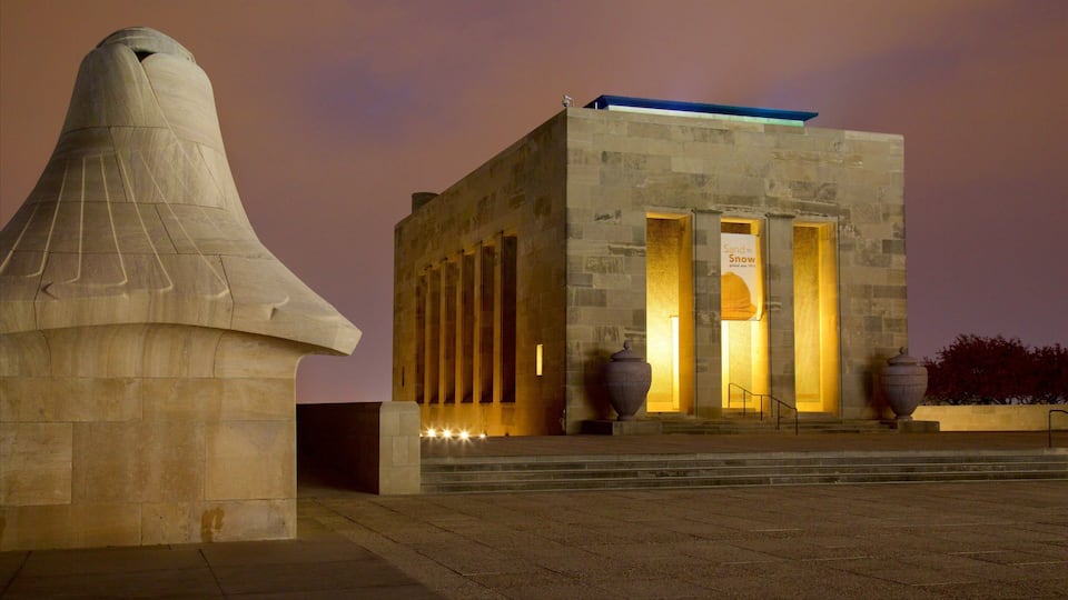 A stone structure with a conical top and a building with columns and a banner.