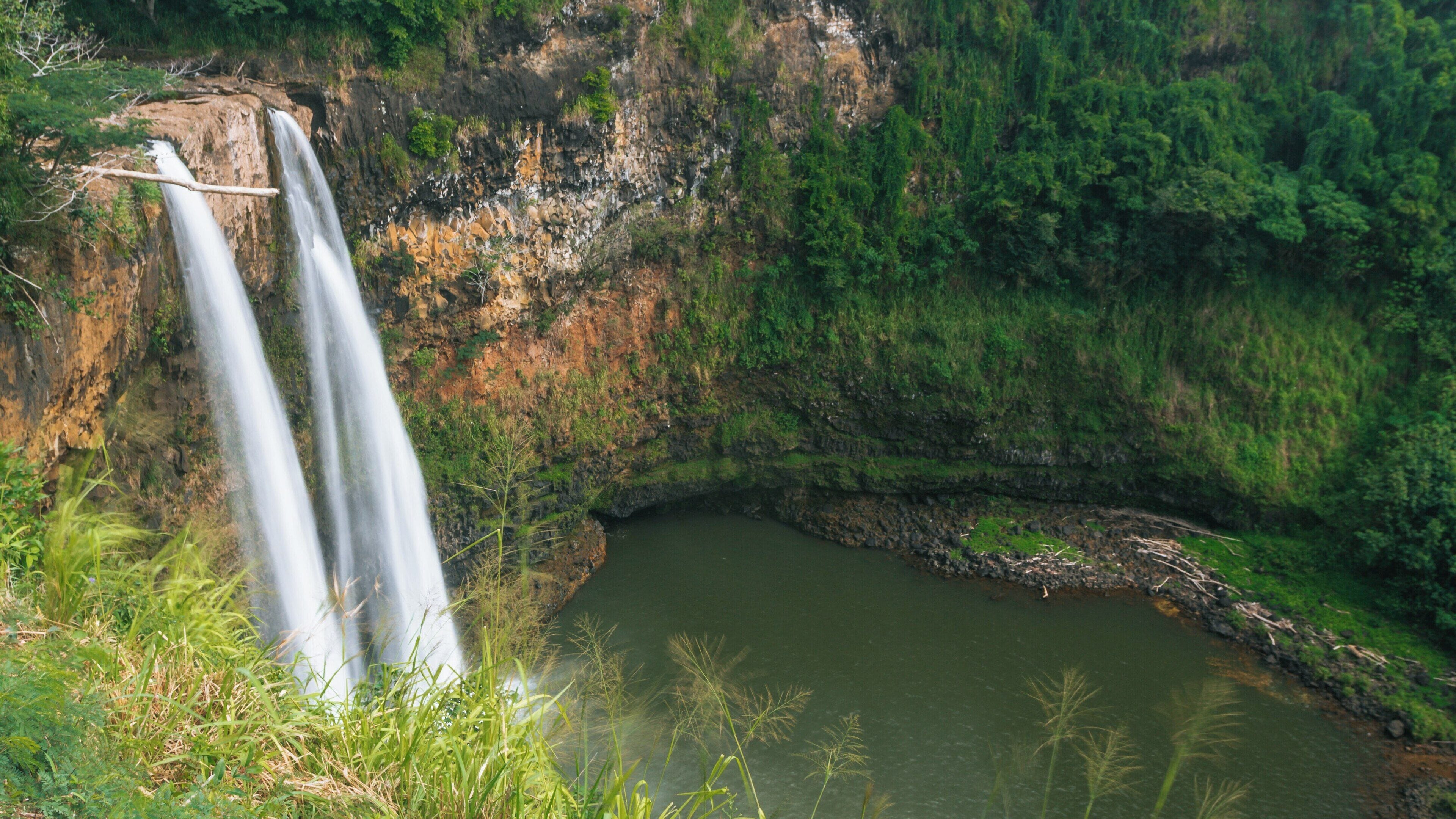 Wailua Falls cascading into a serene pool surrounded by lush greenery in Kapaa, Hawaii during daylight hours