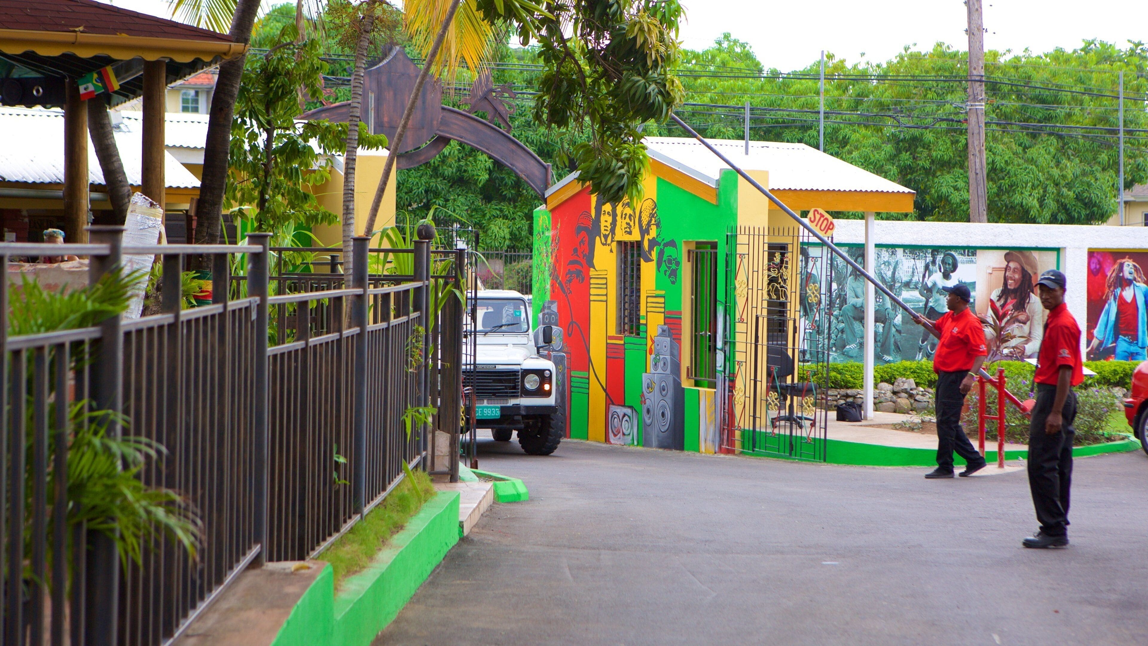A colorful building with murals, a metal fence, and a parked truck.