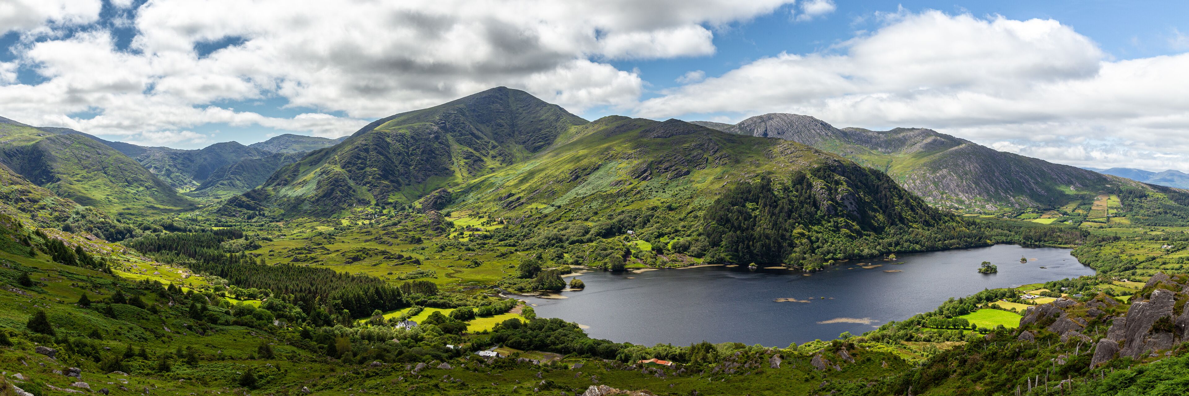 A mountainous landscape with a lake surrounded by lush greenery and scattered houses.
