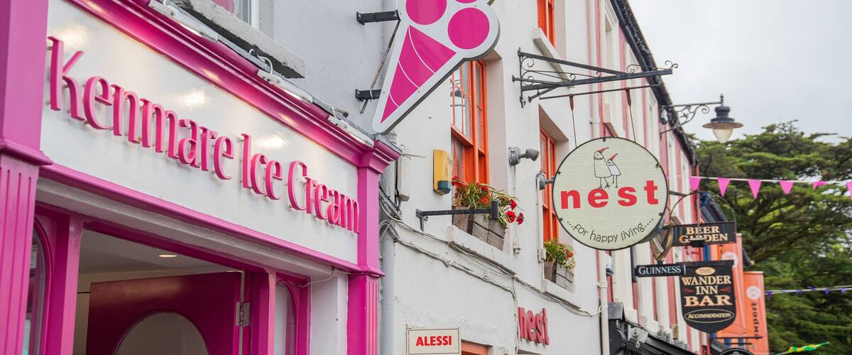 A pink storefront named Kenmare Ice Cream, a sign for 'nest' with a bird illustration, and a 'Beer Garden' sign.