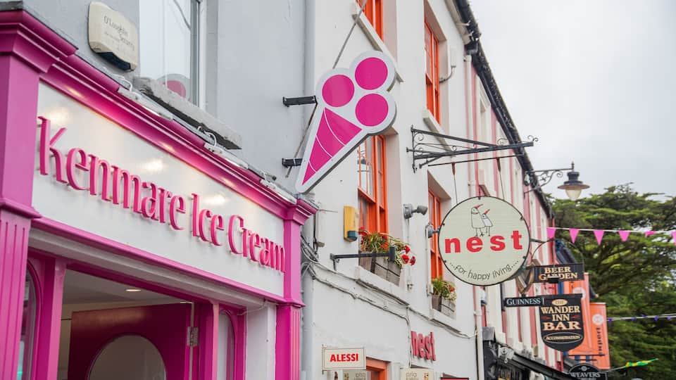 A pink storefront named Kenmare Ice Cream, a sign for 'nest' with a bird illustration, and a 'Beer Garden' sign.
