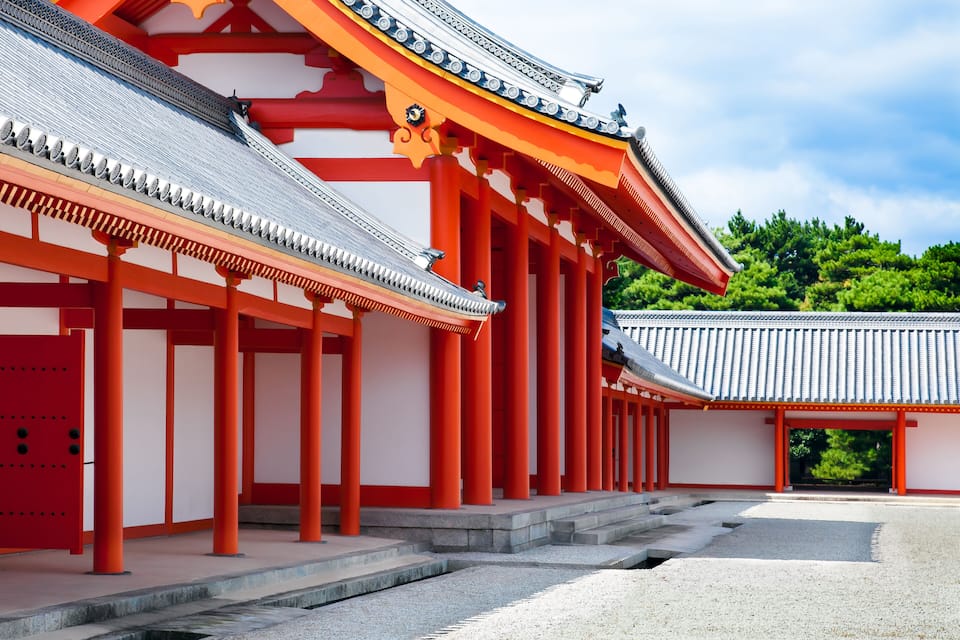 Um templo japonês tradicional com pilares vermelhos e telhado de telhas.