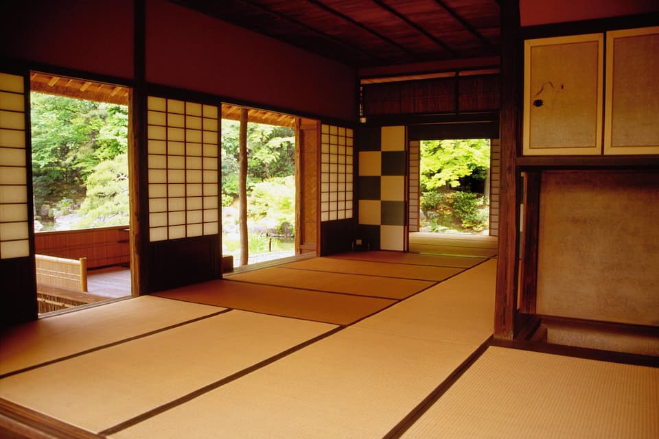 Perinteinen japanilainen huone, jossa on tatamimatto ja liukuvat ovet, jotka johtavat puutarhaan.