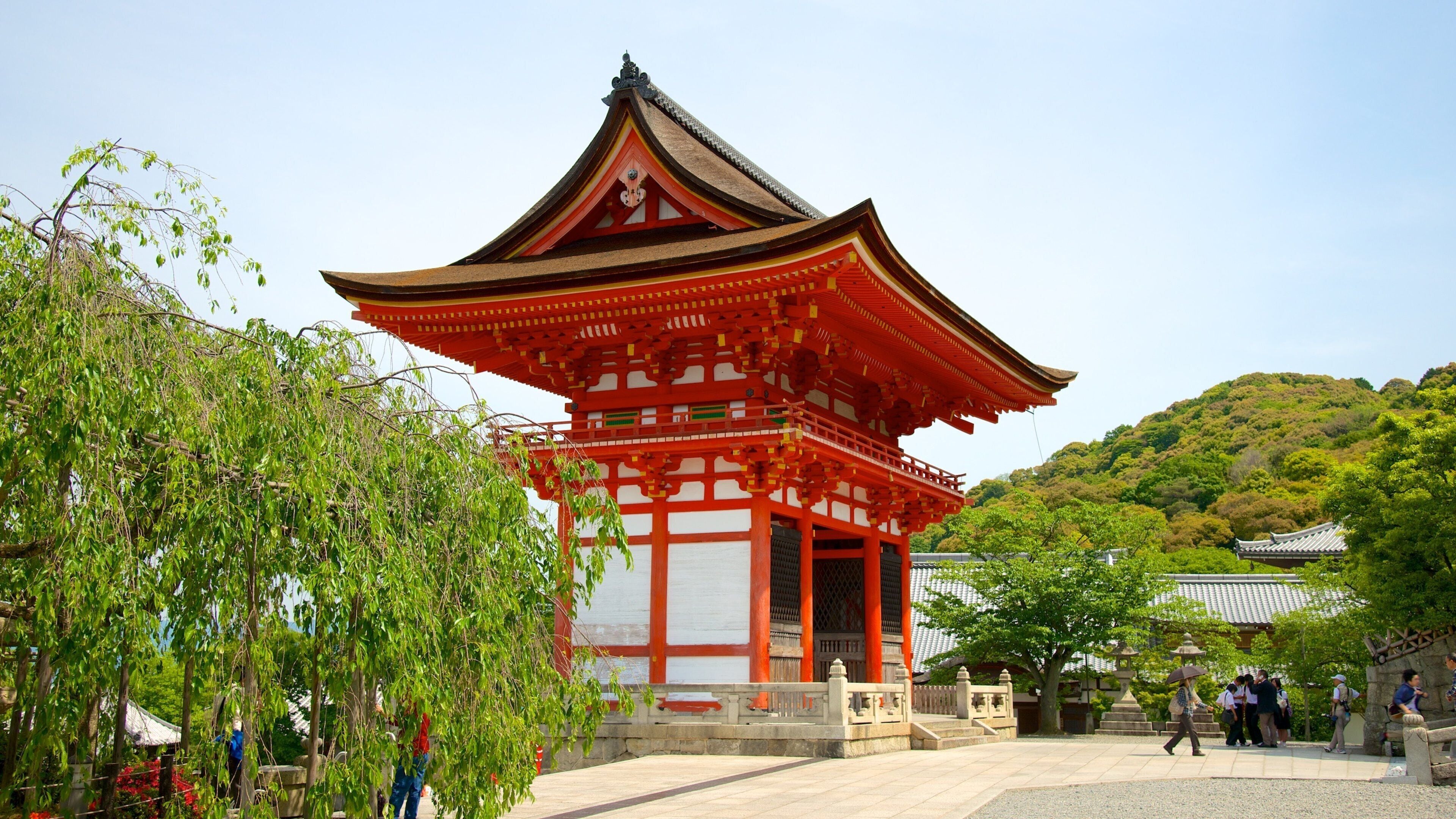 Una pagoda japonesa tradicional con una combinación de colores rojo y blanco, rodeada de exuberante vegetación y un cielo despejado.