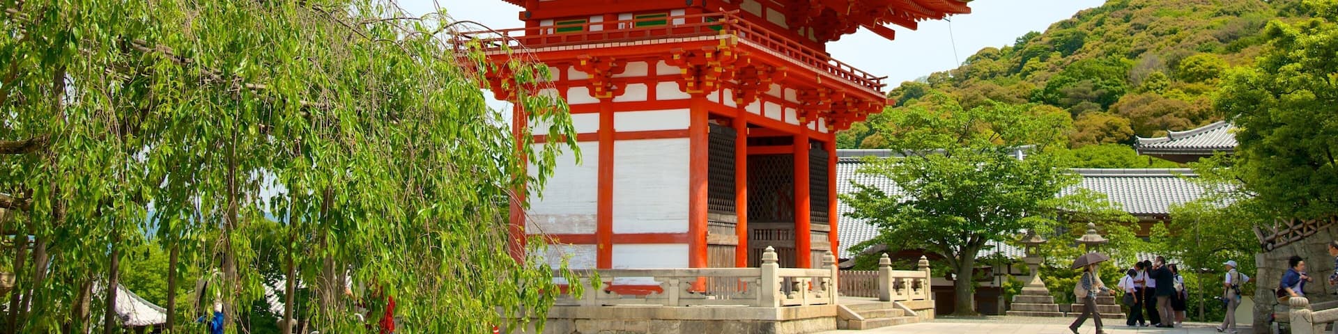 A traditional Japanese pagoda with a red and white color scheme, surrounded by lush greenery and a clear sky.